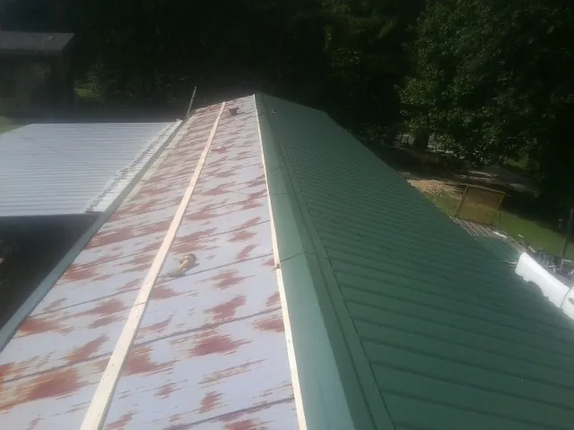 Old rusted panels beside newly installed green metal roofing — Wind Damage Roof Repair by Roofing Brothers in Nolanville