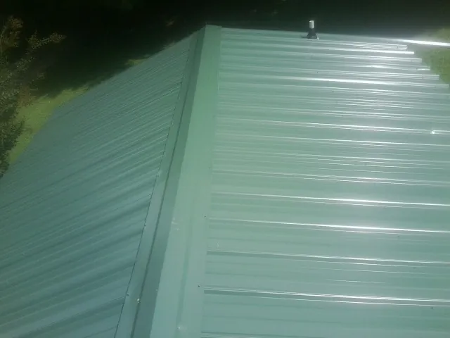 New green metal panels meeting at the ridge of a roof — Flat Roof Repair work by our crew in Nolanville