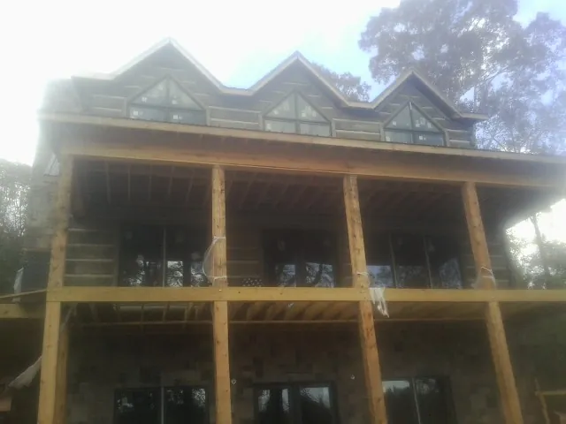 Dormers and porch framing on a large log home under construction — Roof Coating work by our crew in Nolanville