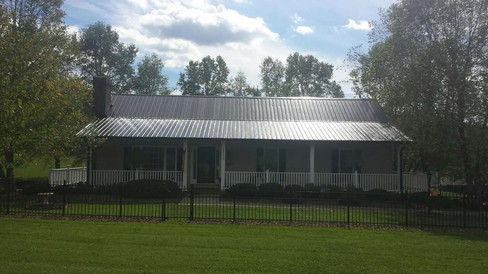 Gray metal roof on a brick ranch with a full width front porch — Gutter Guard Installation work by our crew in Nolanville