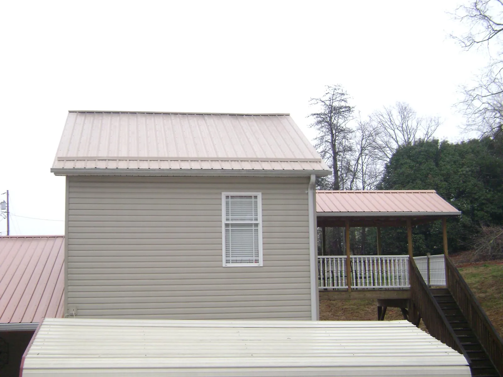 Tan metal roofs on a two story addition and attached porch, from a Roof Replacement job in Nolanville